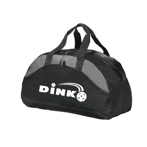 K&ouml;nnte beinhalten: Eine schwarze und graue Sporttasche mit zwei Tragegriffen und einem Rei&szlig;verschluss. Auf der Vorderseite der Tasche befindet sich der wei&szlig;e Schriftzug DINK mit einer Grafik eines gelochten Balls und Bewegungslinien &uuml;ber dem Buchstaben K.