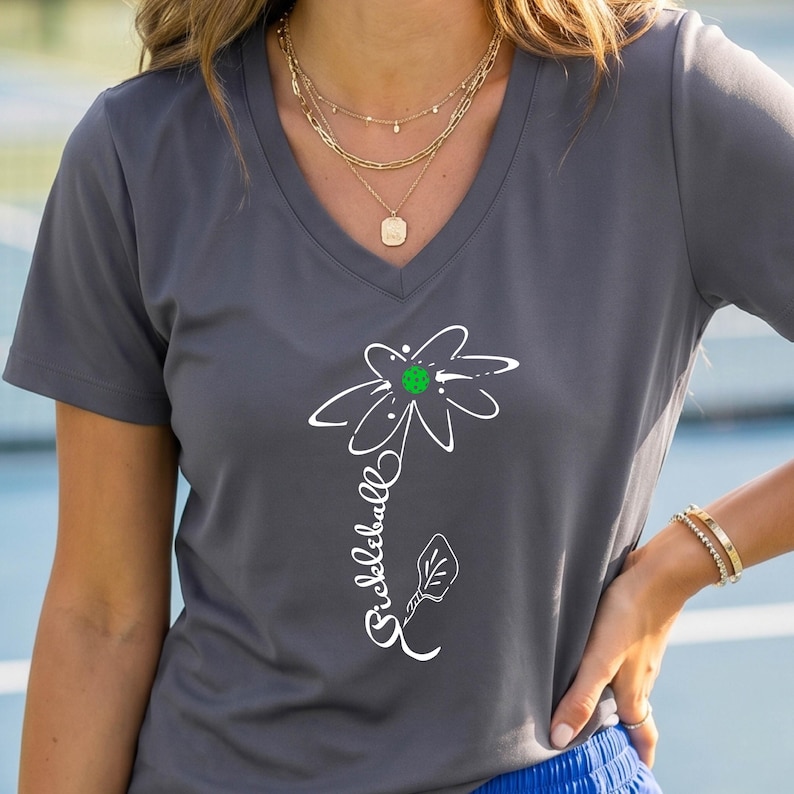 Gray V-neck t-shirt featuring a white flower design with a green center, resembling a pickleball. The word "Pickleball" is written in white script along the stem. The shirt is made of a soft, comfortable material.