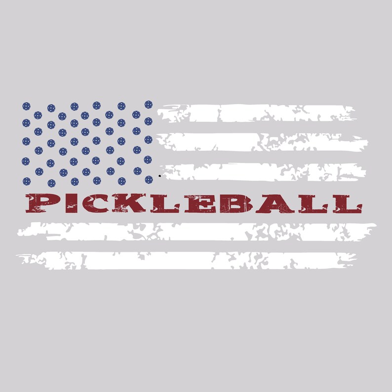 May include: A light gray graphic design featuring a stylized American flag with blue pickleball icons in the canton and distressed white horizontal stripes. The word PICKLEBALL is printed in a bold, dark red, weathered serif font across the center.