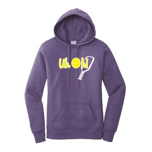 Op de afbeelding: Paarse hoodie met een voorzak en een capuchon met trekkoord. De hoodie heeft de tekst "Uh OK!" in geel, met een pickleball- en paddle-afbeelding. Een casual sweatshirt voor pickleball-liefhebbers.