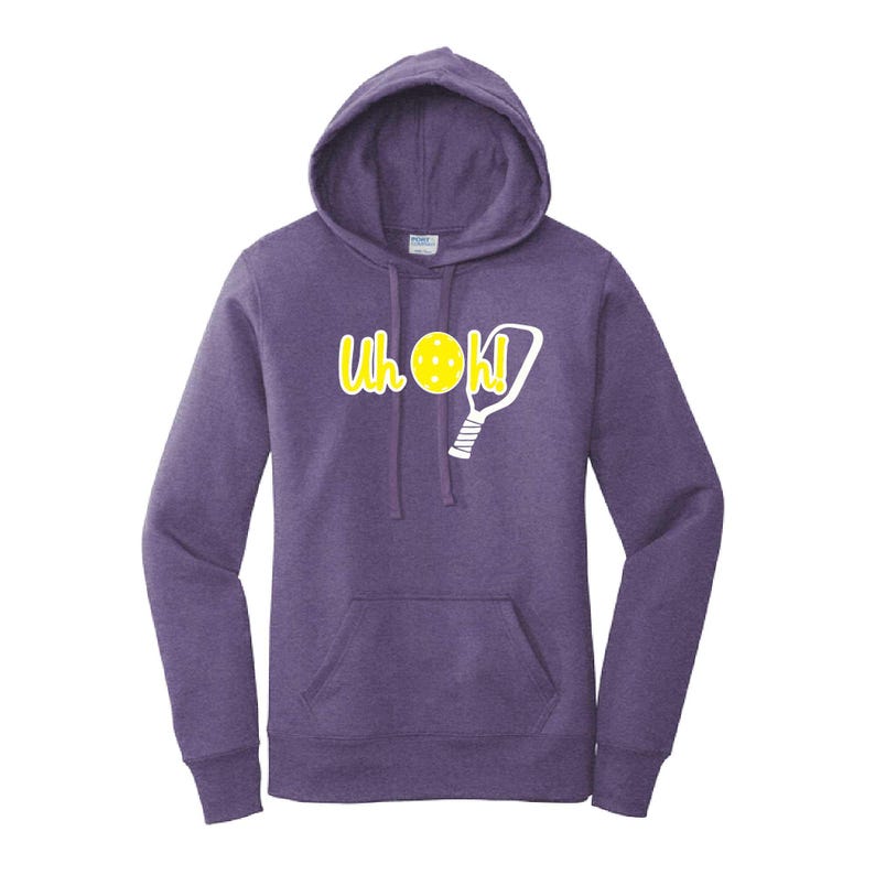 Op de afbeelding: Paarse hoodie met een voorzak en een capuchon met trekkoord. De hoodie heeft de tekst "Uh OK!" in geel, met een pickleball- en paddle-afbeelding. Een casual sweatshirt voor pickleball-liefhebbers.
