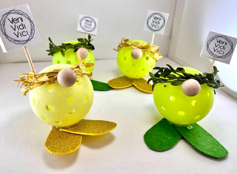 May include: Four yellow and green gnome-like figures with gold glitter accents and a small wooden nose. Each figure has a small sign that reads "veni vidi vici".
