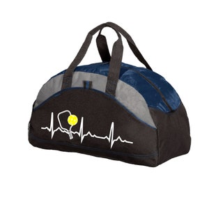 May include: A black, grey and navy blue duffel bag featuring a white heartbeat line graphic with a white pickleball paddle outline and a yellow pickleball. The bag has two black top handles and a zipped main compartment for storage.