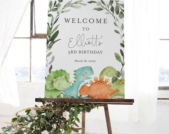 May include: Welcome to Elliott's 3rd Birthday sign with a green leafy border and a watercolour illustration of four dinosaurs. The sign is on a wooden easel.