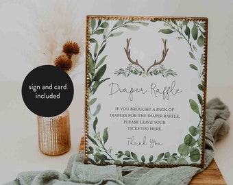 May include: A white sign with a gold frame and green foliage border. The sign says "Diaper Raffle" and includes the text "If you brought a pack of diapers for the diaper raffle, please leave your ticket(s) here. Thank you".