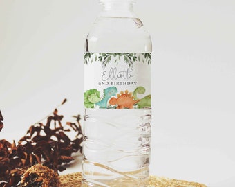 May include: A clear plastic water bottle with a green, white, and orange label. The label features a leafy border and the text "Elliott's 2nd Birthday" with a cartoon image of four dinosaurs.