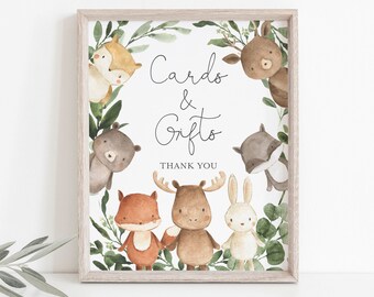 May include: A white card with a brown wooden frame. The card has a wreath of green leaves and woodland animals surrounding the text "Cards & Gifts" with the words "Thank You" below.