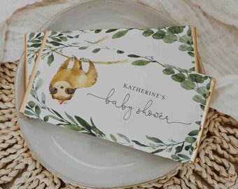May include: A white card with green foliage and a sloth hanging from a branch. The card says "Katherine's Baby Shower" in cursive.