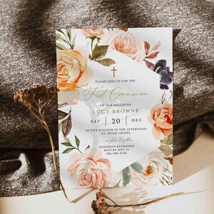 Peut inclure: Une invitation de Première Communion avec un motif floral à l'aquarelle. L'invitation présente une croix, le texte "Première Communion", et des détails tels que le nom de la fille, la date, l'heure et le lieu. L'invitation est ornée de roses pêche et crème.
