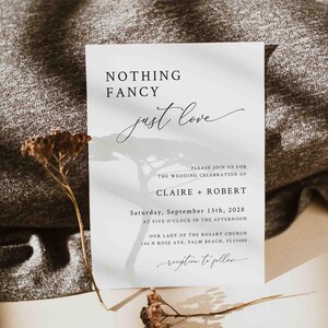 May include: A minimalist wedding invitation with a simple design. The invitation features the text "Nothing Fancy just love" in a handwritten font. The invitation also includes the names Claire and Robert, the date and time of the wedding, and the location of the ceremony.