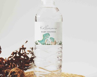 Puede incluir: Una botella de agua de plástico transparente con una etiqueta blanca que dice "Baby Shower de Katherine" y presenta un dinosaurio verde con un bebé dinosaurio en un huevo.