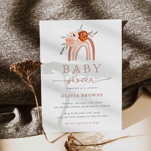 Puede incluir: Una invitación de baby shower blanca con un arcoíris de acuarela y un diseño floral. El texto dice "BABY shower" y "Por favor, únase a nosotros para celebrar a Olivia Browne". La invitación incluye la fecha, la hora, la ubicación y la información de RSVP.