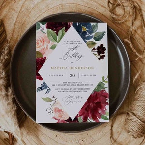 May include: A white invitation card with a floral design in shades of burgundy, pink, and blue. The text on the card reads "Please join us to celebrate the 50th Birthday of Martha Henderson, September 20, 3:00-5:00PM, The Blushed Oak, 144 N County Rd, Palm Beach, FL33480, RSVP to Mila by September 15th, milaanderson@gmail.com, All the best!"