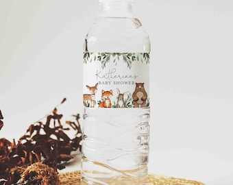 May include: Water bottle label with a woodland theme. The label features a deer, fox, rabbit, and bear with green foliage. The text on the label reads "Katherine's Baby Shower".
