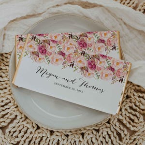 Könnte beinhalten: Weiße Hochzeitsgeschenkschachtel mit goldener Verzierung und floralem Design. Die Schachtel trägt den Text "Megan und Thomas" und "September 20, 2022".