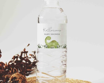 May include: A clear plastic water bottle with a white label that says "Katherine's Baby Shower" and features a green dinosaur illustration.