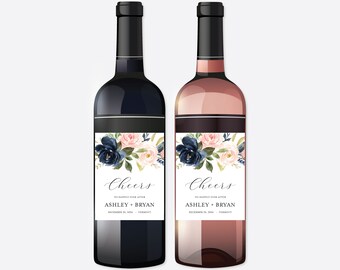 Könnte beinhalten: Zwei Weinflaschen, eine rote und eine Rosé, mit schwarzen Kappen und floralen Etiketten. Die Etiketten zeigen marineblaue und rosa Blumen mit dem Wort "Cheers" und den Namen "Ashley + Bryan".