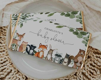 May include: A white card with green leaves and woodland animals printed on it. The card says "Charlotte's Baby Shower".