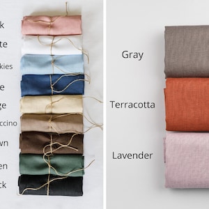 May include: A collection of folded fabric swatches in various colours labelled Pink, White, Blue skies, Blue, Beige, Cappuccino, Brown, Green, Black, Gray, Terracotta, and Lavender. Each swatch is tied with a thin piece of twine string.
