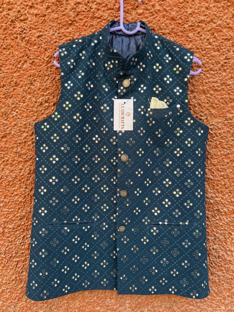 May include: A dark teal vest with a repeating pattern of small, reflective squares. The vest has a mandarin collar, a pocket, and gold-colored buttons. A tag with the text "LEADCRAFTS" is attached.