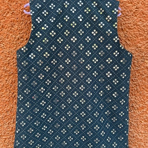 May include: A dark navy blue vest with a quilted pattern and small, reflective embellishments. The vest is sleeveless and has a mandarin collar. The embellishments are arranged in a repeating floral pattern across the vest's surface.