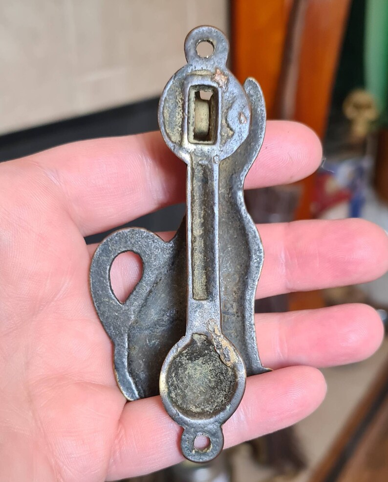 May include: Antique brass door knocker shaped like a dog. The knocker has a detailed design and a round, flat base.