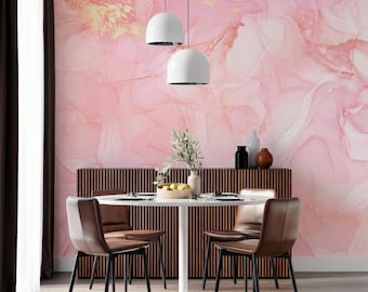 Peut inclure: Un ensemble de salle à manger composé d'une table ronde blanche et de quatre chaises en cuir marron, devant un mur au papier peint à motif marbré rose et doré. Deux suspensions blanches sont installées au-dessus de la table avec une plante.