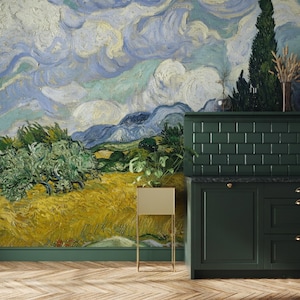 May include: A wall mural featuring a post-impressionist landscape painting with a golden wheat field, green olive trees, and a swirling blue sky with white clouds. A dark green cabinet with a rectangular planter sits in front of the mural.