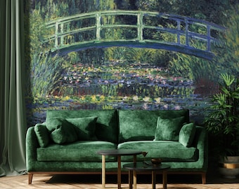 May include: A deep green velvet sofa with two matching throw pillows, positioned in front of a large wall mural depicting a Japanese bridge over a pond with water lilies. Two small round dark metal tables sit in front of the sofa.