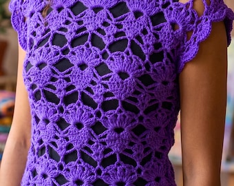 Pode incluir: Um top de crochê em roxo vibrante com um padrão intrincado de pontos abertos, bordas recortadas e mangas curtas. A peça é construída com um design de pontos repetitivos inspirado em flores, criando uma textura semitransparente.