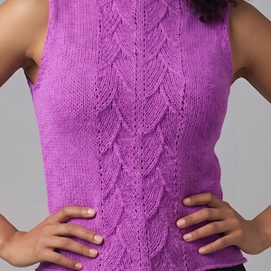 May include: A sleeveless knit top in a vibrant purple hue, featuring a prominent vertical panel of textured leaf-like cable stitches running down the center. The garment has a simple round neckline and a straight hemline with a subtle rolled edge.
