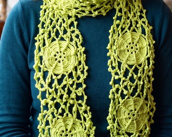 Può includere: Una sciarpa all'uncinetto color verde lime caratterizzata da una serie di motivi circolari a forma di ruota collegati da un motivo a rete aperto e arioso. La sciarpa è realizzata in filato e presenta un punto coerente e complesso.