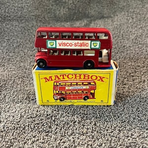 May include: Red double-decker bus toy with "visco-static BP" printed on the side. The toy is in its original Matchbox box, which says "Matchbox Series" and "A Lesney Product".