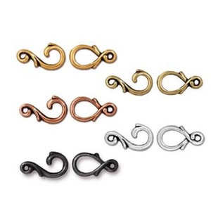 May include: Set of six ornate metal clasps in gold, silver, copper, and black finishes. Each clasp features a decorative swirl design.