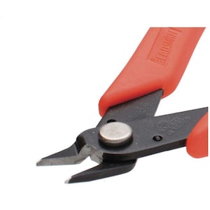 May include: Close-up of a pair of black and silver wire cutters with red handles. The tool has a silver rivet and the brand name "Beadsmith" is printed on the red handle. The blades are angled and sharp.