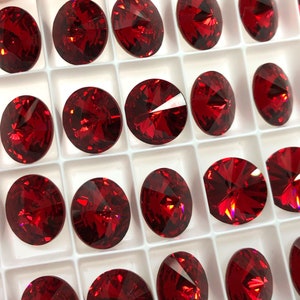 Puede incluir: Una vista cercana de una bandeja de piedras de cristal rojo. Las piedras están dispuestas en un patrón de cuadrícula y todas son del mismo tamaño y forma.