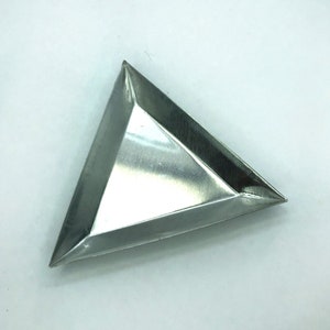 May include: A triangular, silver-colored metal tray with a brushed finish. The tray has three sides and pointed corners. The interior of the tray is smooth and reflective. The tray is empty and sits on a white surface.