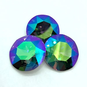 May include: Three iridescent round glass rhinestones with a faceted design. The rhinestones are green, blue, and purple.