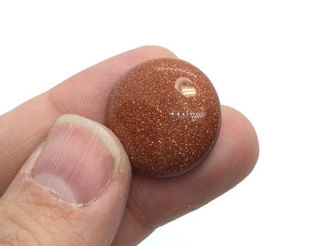 May include: A round, polished, red-brown gemstone with a glittery surface.