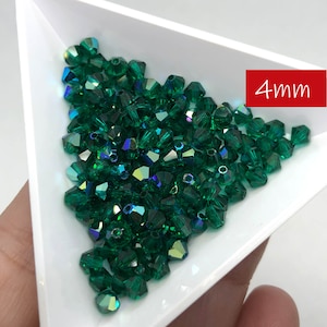 May include: A close-up of a pile of 4mm emerald green crystal beads. The beads are faceted and have a shiny, iridescent finish.