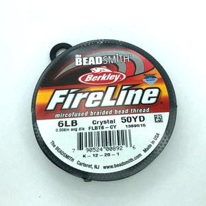 May include: A spool of black FireLine mircofused braided bead thread by Berkley Beadsmith. The spool is labeled with the text "6LB 0.006in avg.dia FLBT6-CY Crystal 50YD 1389515".