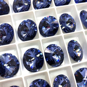 May include: A close-up view of a tray of blue crystal rhinestones. The rhinestones are arranged in a grid pattern and are all the same size and shape. The rhinestones are sparkling and reflecting light.