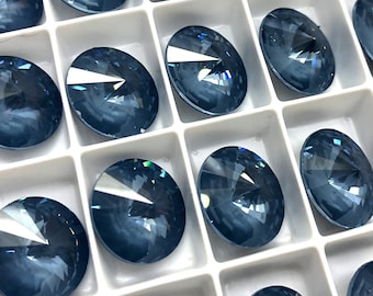 May include: A close-up view of a tray of round, blue, faceted rhinestones. The rhinestones are arranged in a grid pattern and are all the same size.