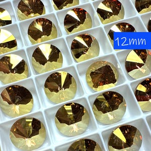 Puede incluir: Una vista cercana de una bandeja de 12 mm de strass redondos, facetados, de vidrio ámbar. Los strass están dispuestos en un patrón de cuadrícula y todos son del mismo tamaño y forma.