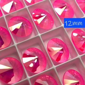 May include: A close-up of a tray of 12mm pink iridescent round rhinestones. The rhinestones are arranged in a grid pattern and are all the same size. The rhinestones are shiny and have a rainbow effect.