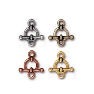 May include: Four toggle clasps in different finishes: silver, antique brass, copper, and gold. Each clasp features a round ring with a bar that slides through it.