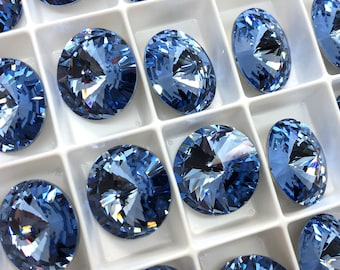 May include: A close-up view of a tray of light blue round rhinestones. The rhinestones are arranged in a grid pattern and have a faceted design.