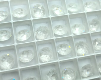 May include: A close-up view of a white plastic tray filled with clear, faceted, iridescent glass stones. The stones are arranged in rows and columns, and they are all the same size and shape.