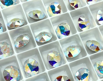 May include: A white tray with rows of iridescent oval-shaped rhinestones. The rhinestones have a rainbow effect and are arranged in a grid pattern.