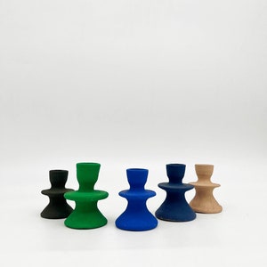Può includere: Cinque portacandele in ceramica di diversi colori: nero, verde, blu, blu scuro e beige. Ogni portacandele ha una forma unica con una base più ampia e una parte superiore più stretta.